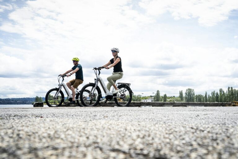 A Couple Wearing Helmets Riding Electric Bikes